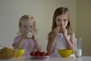 Two sisters eating cereal with milk