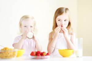 Two sisters eating cereal with milk